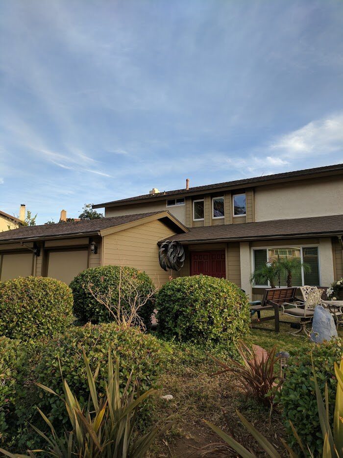 The same two-story house repainted tan with dark trim and a red front door